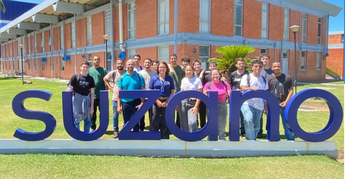 Alunos da UCL no parque industrial da Suzano em volta do logo da empresa.