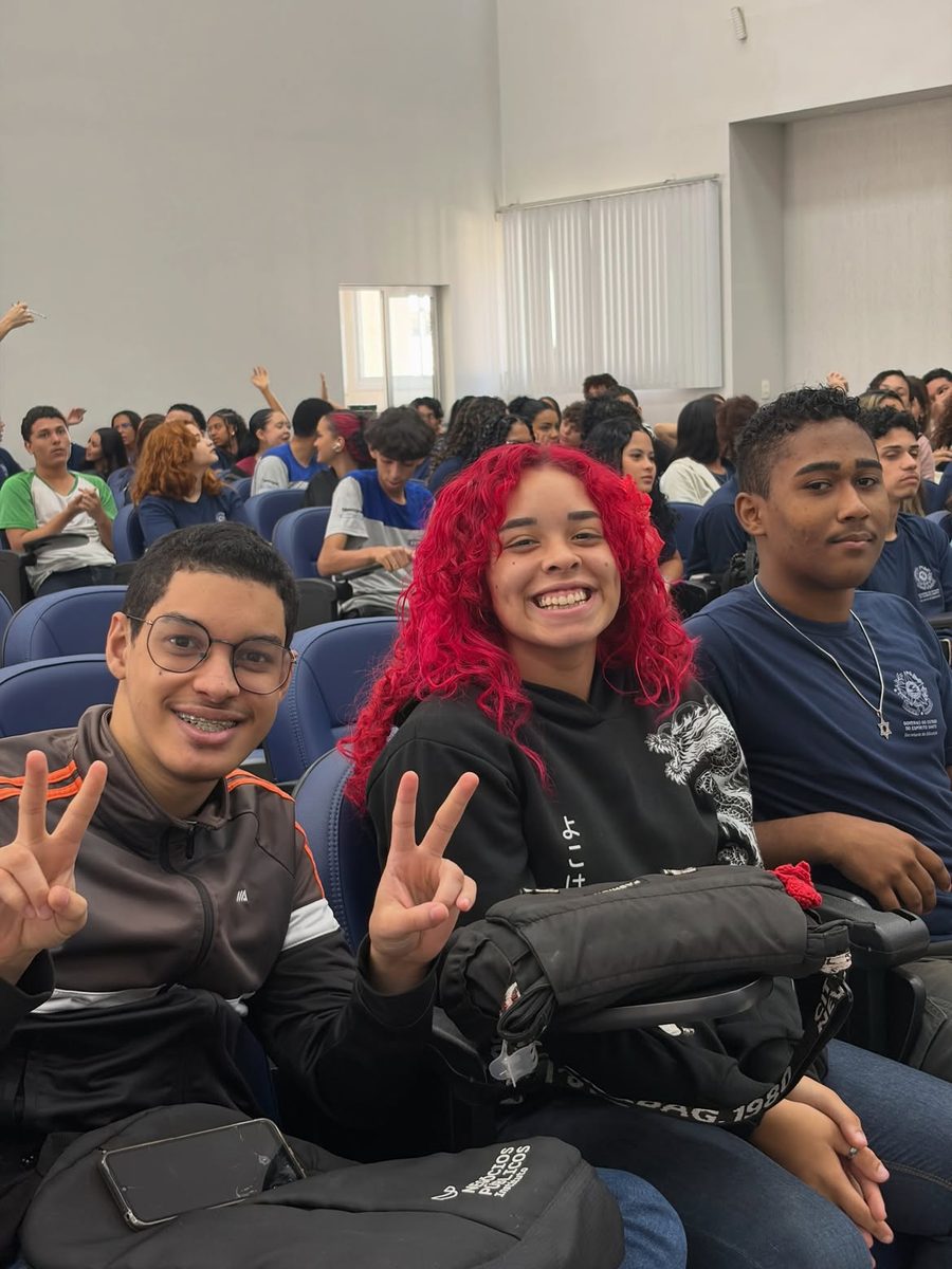 Alunos fazendo gestos de cumprimentos para a câmera.